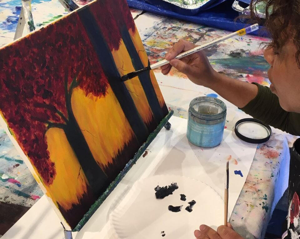 Adult Student Working on Acrylic Painting Adult learner focused on applying acrylic paints to canvas during a lesson.